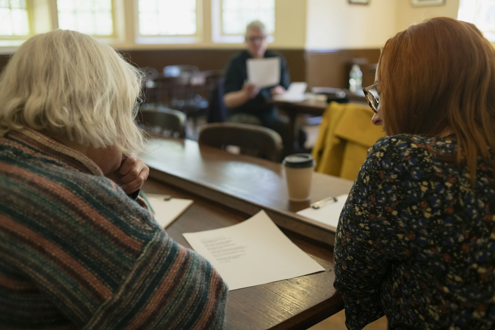 Pflegeberaterin und ältere Frau sitzen gemeinsam am Tisch und gehen Unterlagen durch
